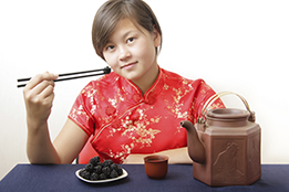 This is a photo of a young woman eating berries with chopsticks.