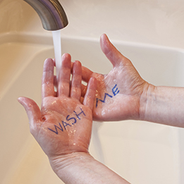 This is a photo of hands being washed. WASH ME is written on the hands in blue ink.