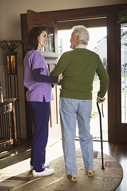This is a photo of a young woman helping an older man walk with a cane.
