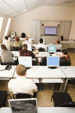A photograph shows students watching a presentation in a computer class.