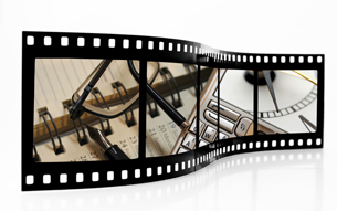 This photograph shows a filmstrip with an organizer, a keyboard, a clock, a pen, and a pair of glasses in it.