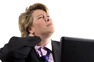 Business women rubbing her neck sitting at her laptop.