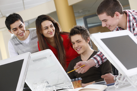 This picture shows three boys and one girl working with computers.