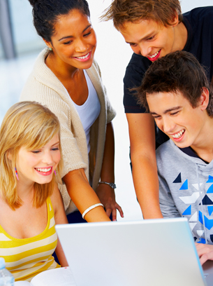 The photograph shows a study group of two young men and two young women smiling as they work on a laptop.