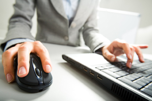 A picture shows a woman working at a computer with a mouse.