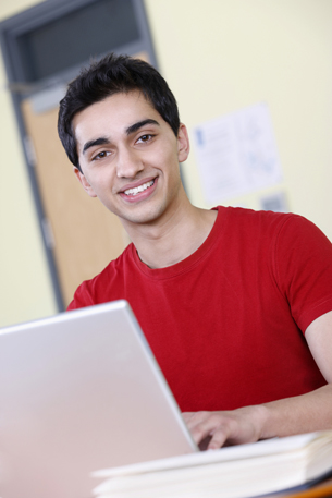 This is a photograph of a young man working at a computer.