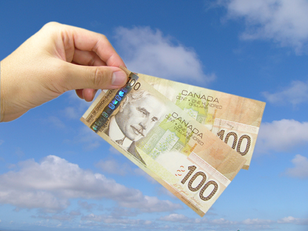 This photograph shows a male hand holding two Canadian hundred-dollar bills.