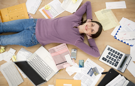 This is a photo of a lady laying on the floor surrounded by office supplies and materials.