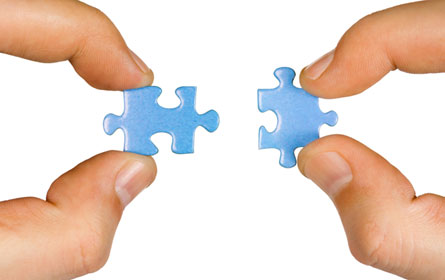 This photograph shows a person putting two puzzle pieces together.