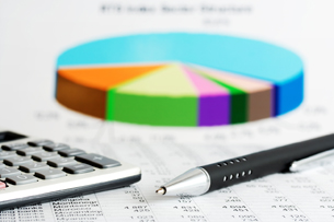 This image shows a pie graph with a calculator and a pen.