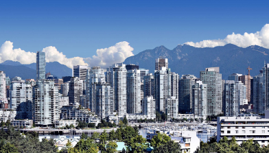 This photo shows Vancouver, British Columbia, with mountains and clouds in the background.