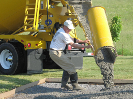 This photograph shows a worker pouring concrete from a truck.