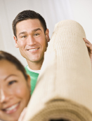 This photograph shows a roll of carpet carried by two people.