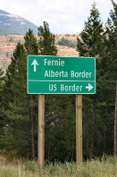 This is a photograph of a road sign in British Columbia. The direction of Fernie and the Alberta border is shown as straight ahead. The direction of the US border is shown as to the right.