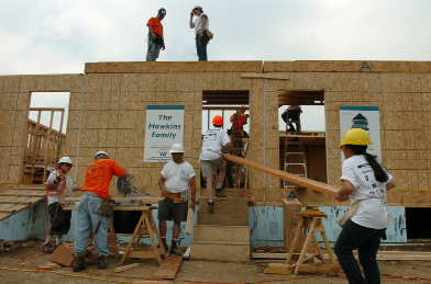 This photograph shows volunteers building a row of new homes.