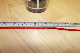 A photograph shows a ribbon placed along the side a tape measure.