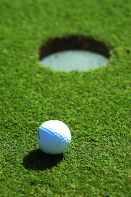 This image shows a golf ball on the green, near the hole.