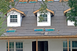 This photo shows a house with bundles of shingles sitting on the roof.