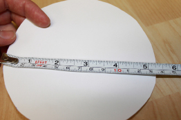 This photo shows a measuring tape lying along the diameter of the paper circle.
