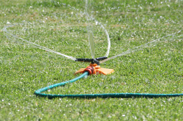 This photograph shows a lawn sprinkler rotating as it sprays water.
