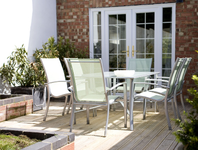 This photograph is of a sunny deck with outdoor furniture.
