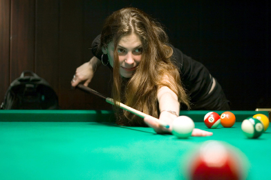 This photograph is of a young woman lining up a shot on a billiard table.