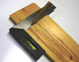 This photo shows a carpenter’s square placed on a board.
