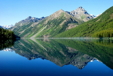 This is a photograph of a mountain landscape reflected in the still waters of a lake.