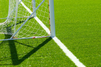 This photograph is of shadows made by the goal posts on a soccer pitch.