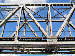 This is a photograph of a railway bridge against a blue sky.