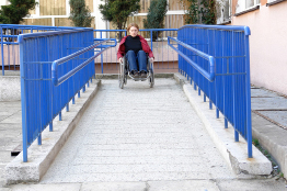 This is a photograph of a woman in a wheelchair descending a ramp.