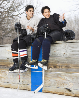 This is a photograph of two youths with hockey sticks.