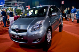 A photo shows a subcompact hatchback car in a showroom.