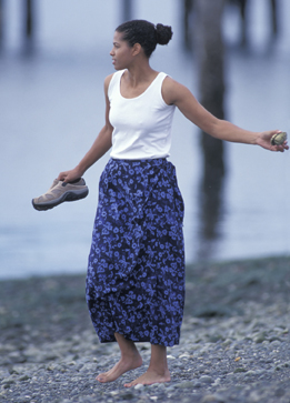This is a photo of a woman throwing a rock into the ocean.