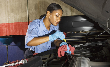 This photo shows a female mechanic fixing a vehicle.