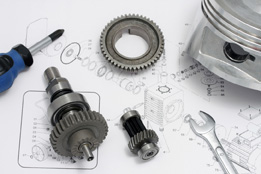 This photo shows some tools and gears sitting on a blueprint.