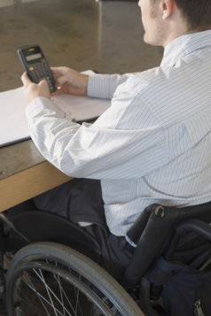 This is a photo of a man in a wheechair using a calculator.